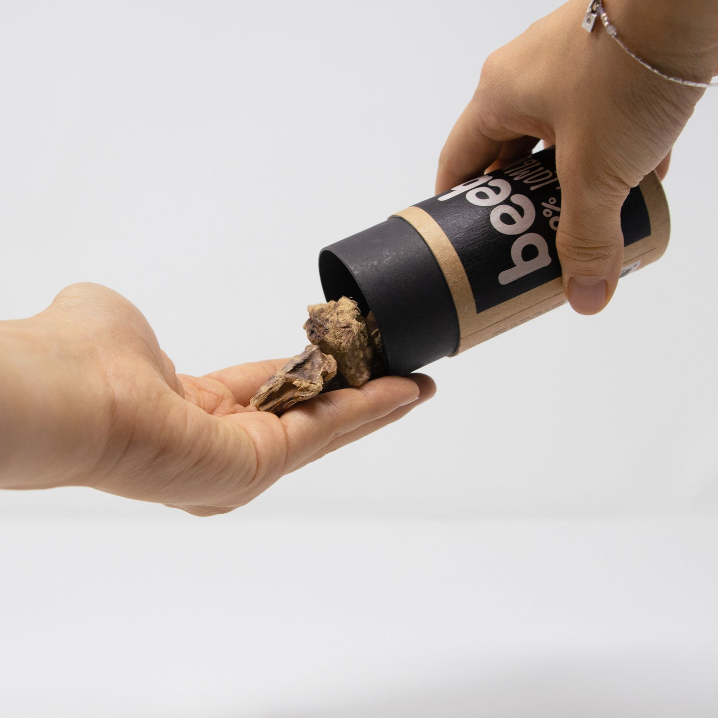 Person holding a container of truffles with one hand on a white background